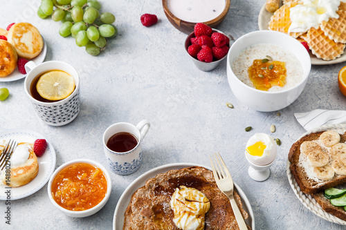 Morning atmosphere. Healthy breakfast with porridge  oatmeal  pancakes  lots of berries and snacks on blue rustic background. Text space at the center.