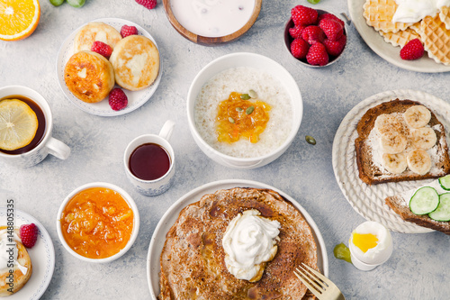 Morning atmosphere. Healthy breakfast with porridge, oatmeal, pancakes, lots of berries and snacks on blue rustic background.