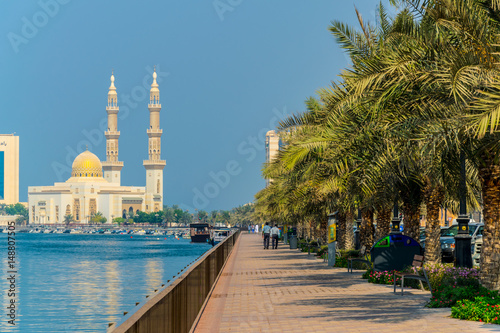 view of riverside promenade in Sharjah with Al Maghfirah mosque at background, UAE photo