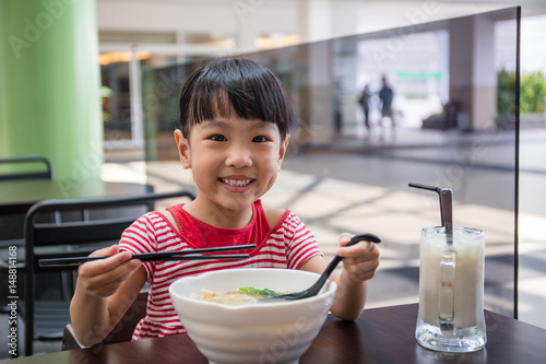 Asian little Chinese girl eating noodles soup