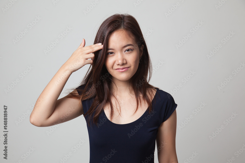 Beautiful young Asian woman holding fingers in gun gesture. Beautiful young Asian woman holding fingers in gun gesture.