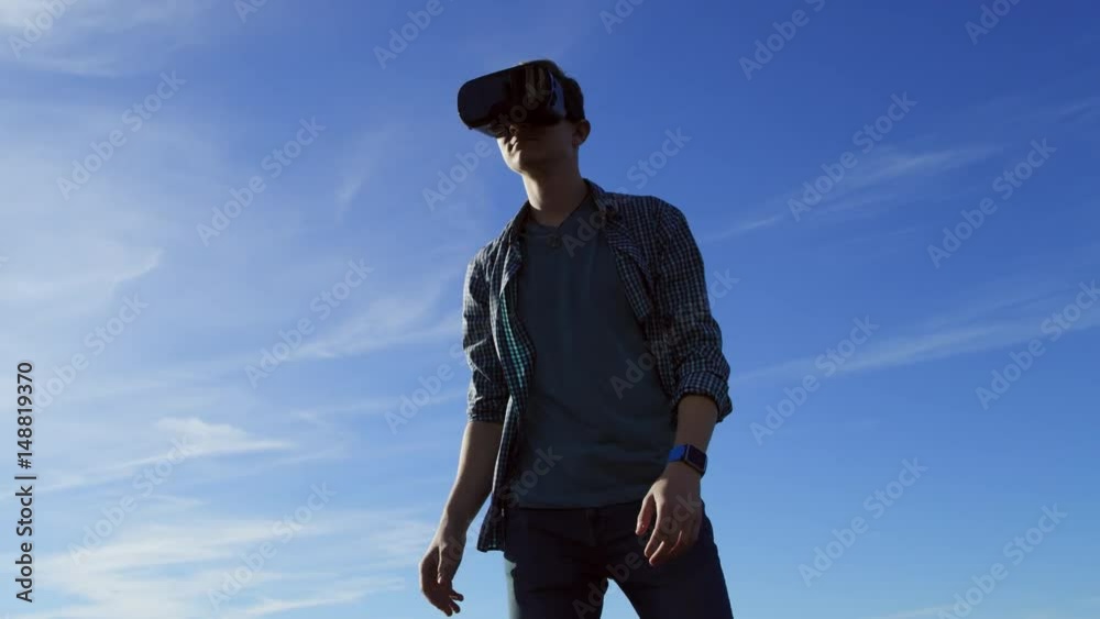 Young man is walking on beach with his virtual reality glasses Young man is walking on beach with his virtual reality glasses