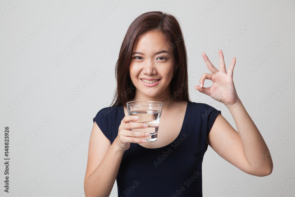 Young Asian woman show OK with a glass of drinking water. Young Asian woman show OK with a glass of drinking water.