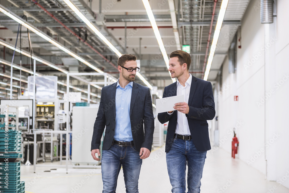 Two men with tablet talking in factory shop floor Two men with tablet talking in factory shop floor