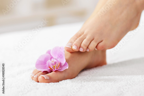 Soft female feet with french pedicure and flowers close up