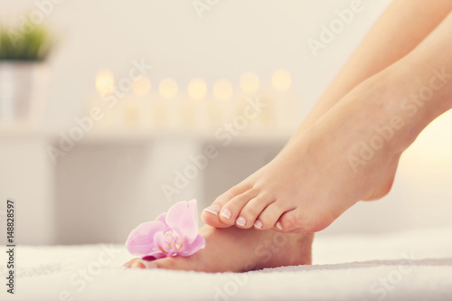 Soft female feet with french pedicure and flowers close up