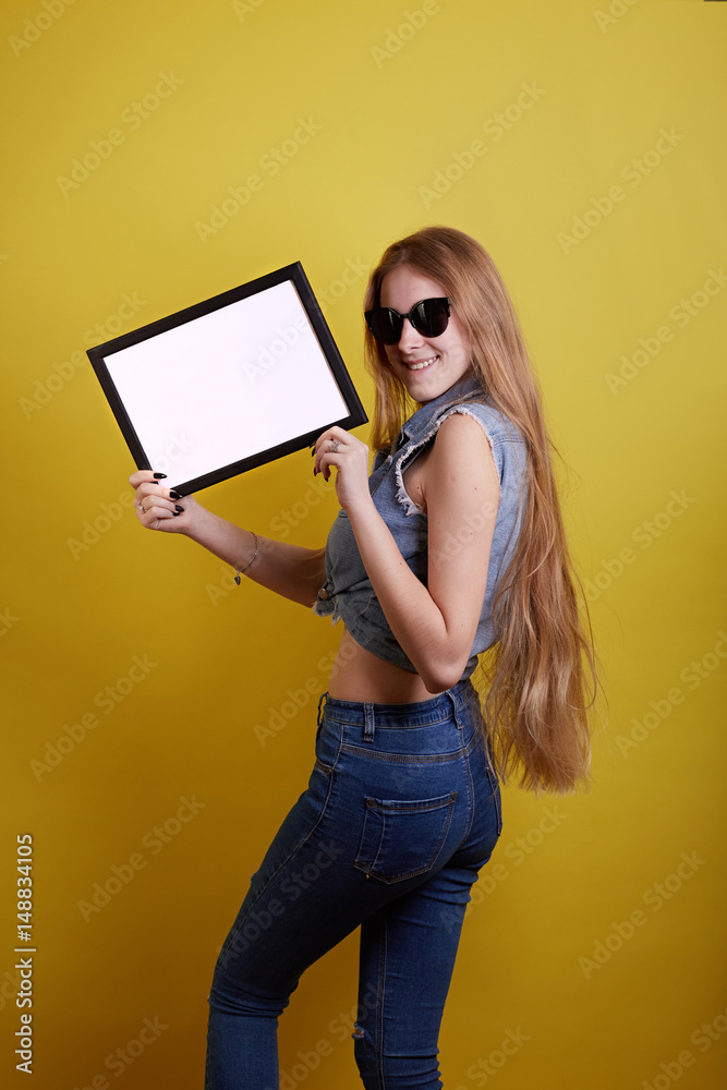 Your text here. Pretty young excited woman holding empty blank board. Colorful studio portrait with a yellow background. Your text here. Pretty young excited woman holding empty blank board. Colorful studio portrait with a yellow background.
