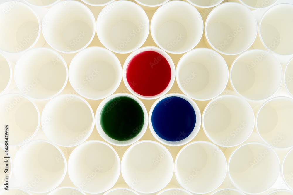 Top view of set of empty plastic cups and cups with red, green and blue paints