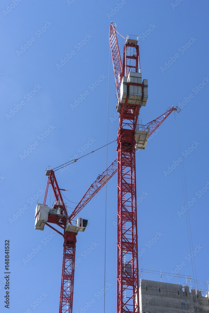 Tall cranes on building site.