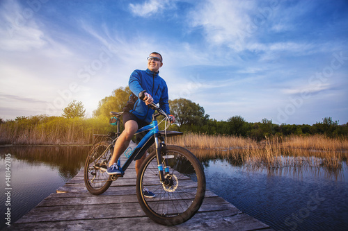 man cyclist Rides on a wooden bridge across the river