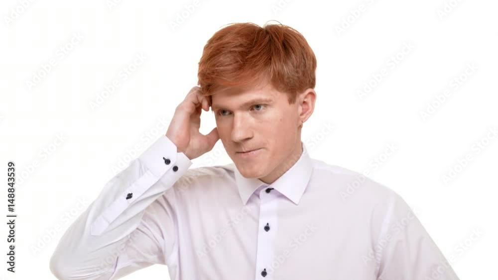 Nervous ginger Caucasian young boy standing on white background shuffling around