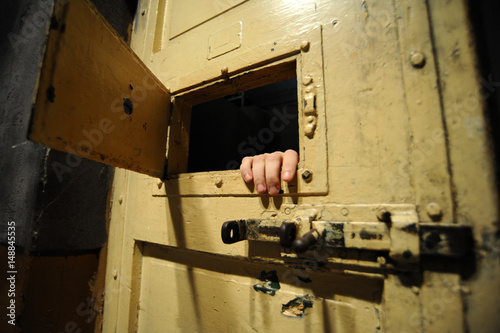 Interior of a bad condition prison cell seen through the door window