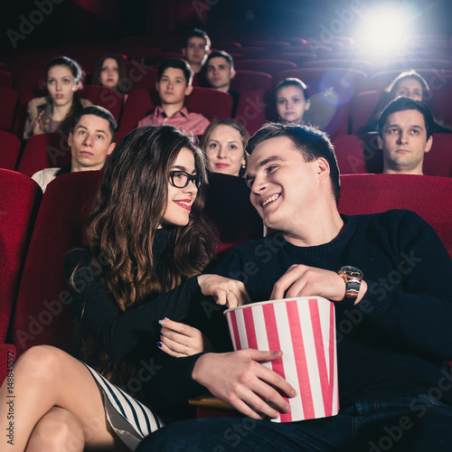 A couple in love flirting at the cinema and eating popcorn