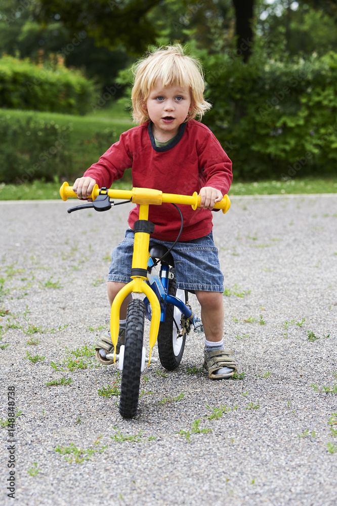 Happy toddler boy riding bike. Kids enjoying a bicycle ride. Sport concept. First bike for little child. Active toddler kid playing and cycling outdoors. Happy toddler boy riding bike. Kids enjoying a bicycle ride. Sport concept. First bike for little child. Active toddler kid playing and cycling outdoors.