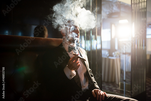 Photography A brutal man in a dress coat smokes a cigar.