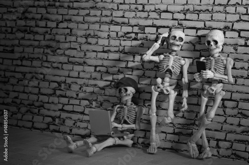 Three skeletons with smartphone and laptop 