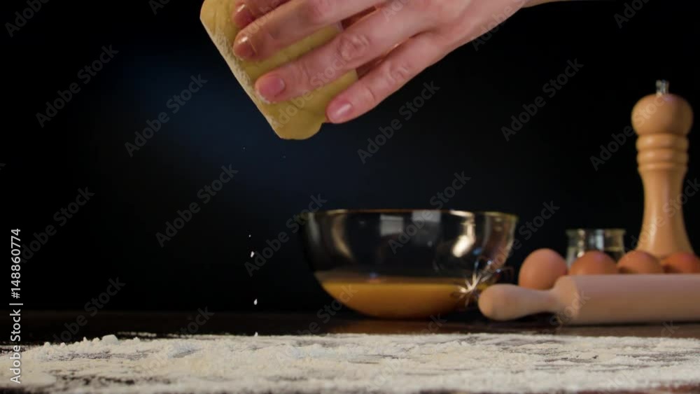 Female hands kneading dough on the table against a dark background. Close-up shot Female hands kneading dough on the table against a dark background. Close-up shot