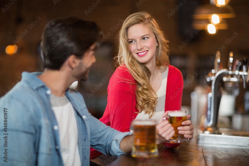 Man and woman looking at each other with holding beer glasses Man and woman looking at each other with holding beer glasses