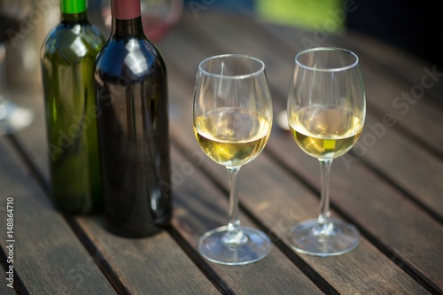 White wine in glasses by bottles on table