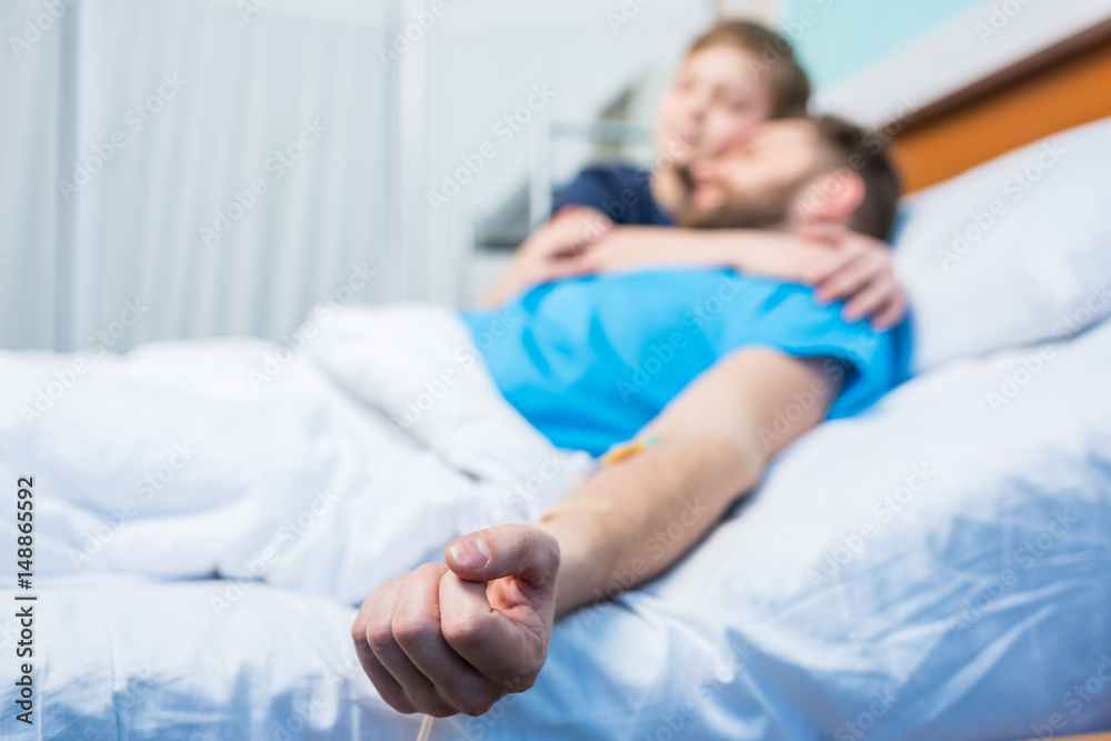 Father With Son Embracing While Laying On Hospital Bed At Ward Dad And