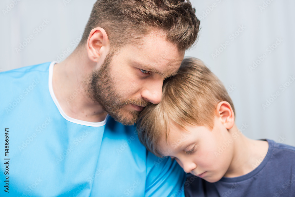 Close-up view of sick father and upset son together, dad and son in hospital Close-up view of sick father and upset son together, dad and son in hospital