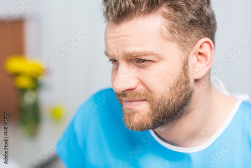 Close-up portrait of sick bearded man looking away in hospital