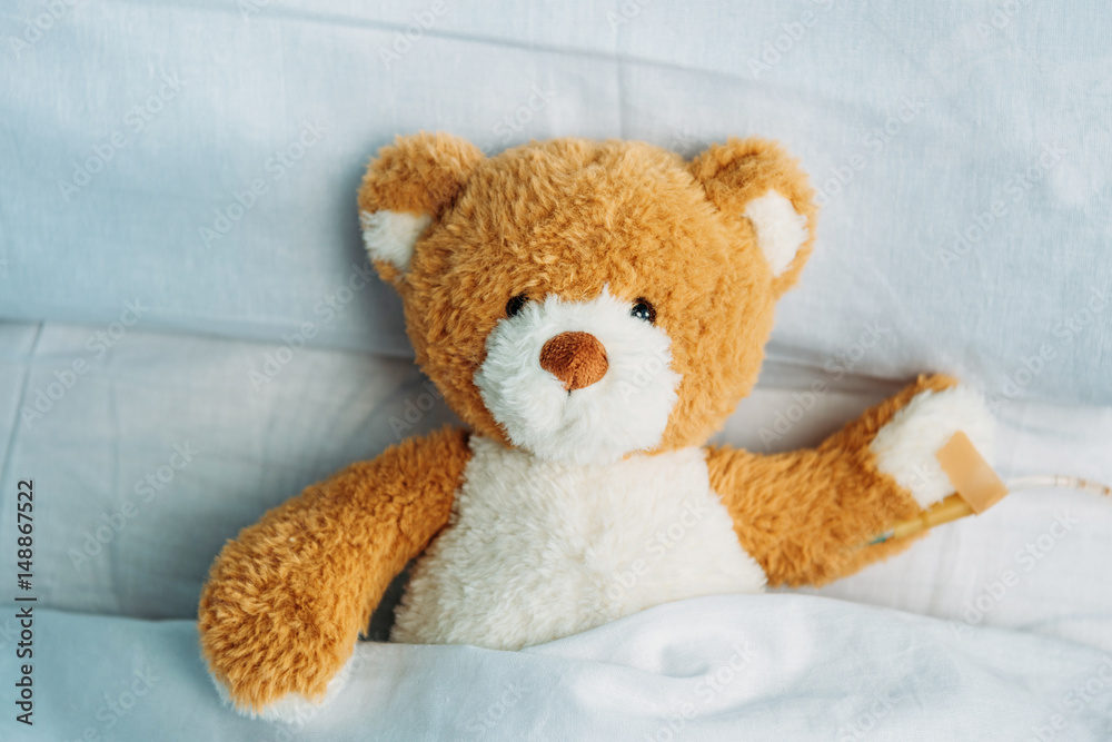 close up view of cute teddy bear toy lying in bed with drop counter