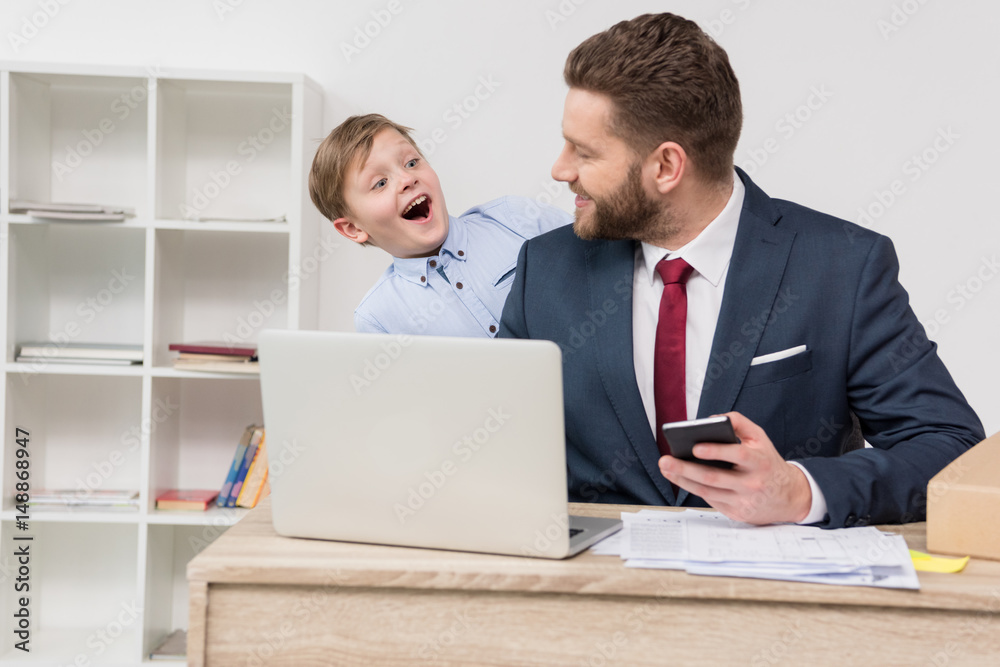 Naughty boy with his father businessman at office Naughty boy with his father businessman at office