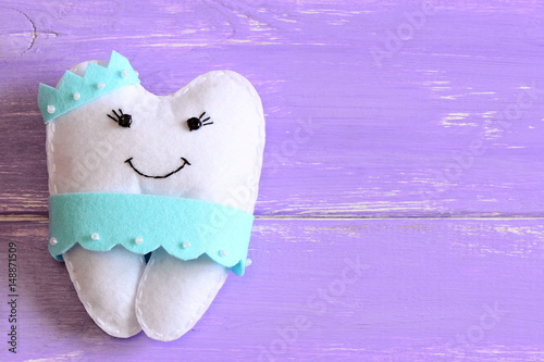 Felt tooth fairy pillow isolated on wooden background with copy space for text. Handmade children's felt tooth fairy pillow. Stuffed toy crafts idea. Top view. Closeup