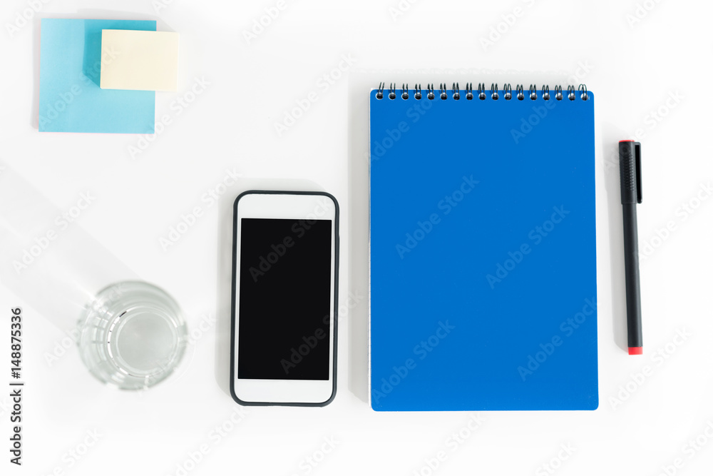 Top view of smartphone with blank screen, notebook with pen, glass of water and sticky notes Top view of smartphone with blank screen, notebook with pen, glass of water and sticky notes