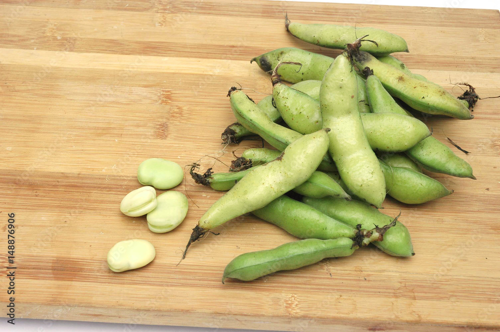 fresh broad beans on bamboo cutting board fresh broad beans on bamboo cutting board