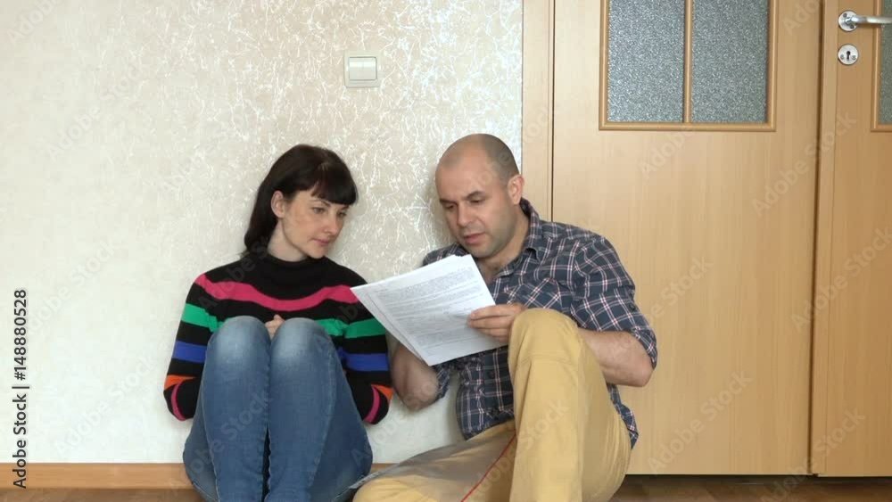 Husband and wife are looking at unpaid bills. Married couple cussing while sitting on the floor. Peopls is bankrupt. Husband and wife are looking at unpaid bills. Married couple cussing while sitting on the floor. Peopls is bankrupt.