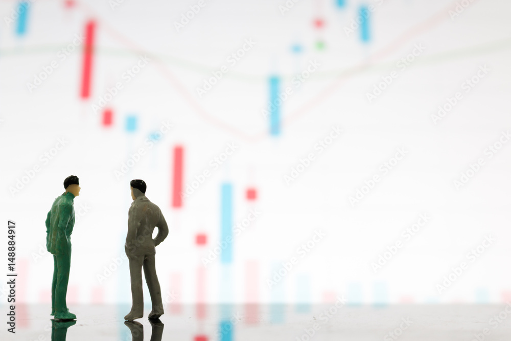 Fototapeta premium Miniature figures businessman standing on a graph chart