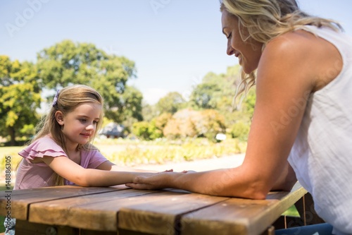 Mother and daughter holding hands on picnic table