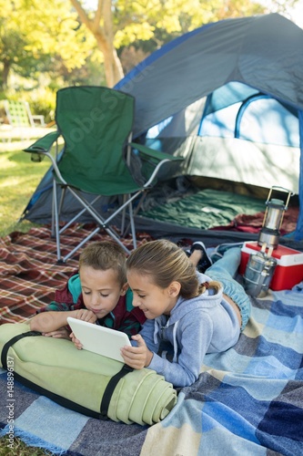 Siblings using laptop outside the tent © WavebreakMediaMicro