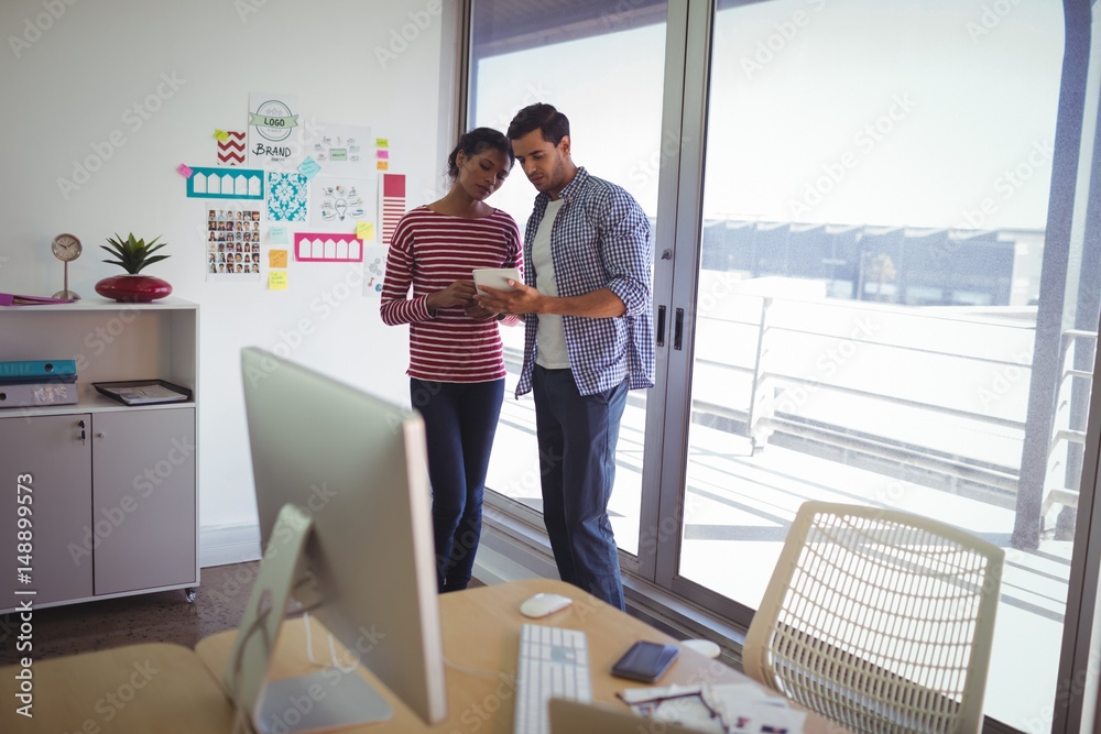Colleagues discussing over digital tablet in office