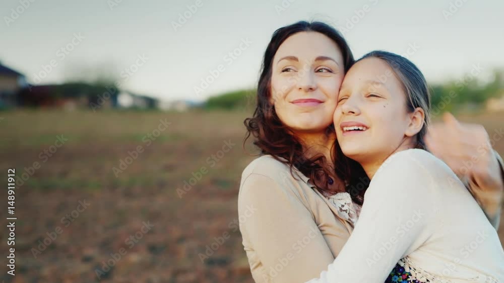 Mama gently hugs her daughter for 11 years. Together they look in one direction to the setting sun. Family values Mama gently hugs her daughter for 11 years. Together they look in one direction to the setting sun. Family values