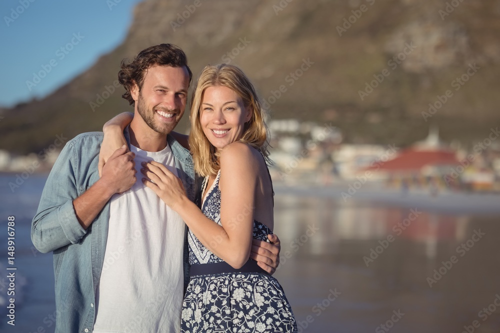 Naklejka premium Portrait of happy young couple embracing at beach