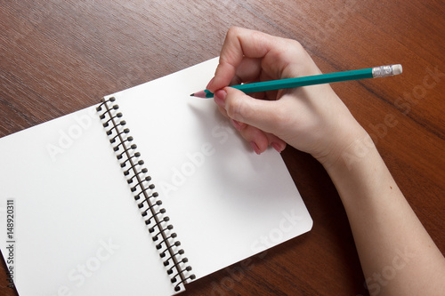 Closeup photo of girl writing in notebook with pencil