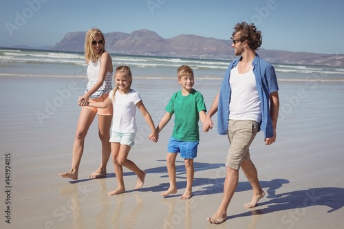 Happy family holding hands while walking at beach