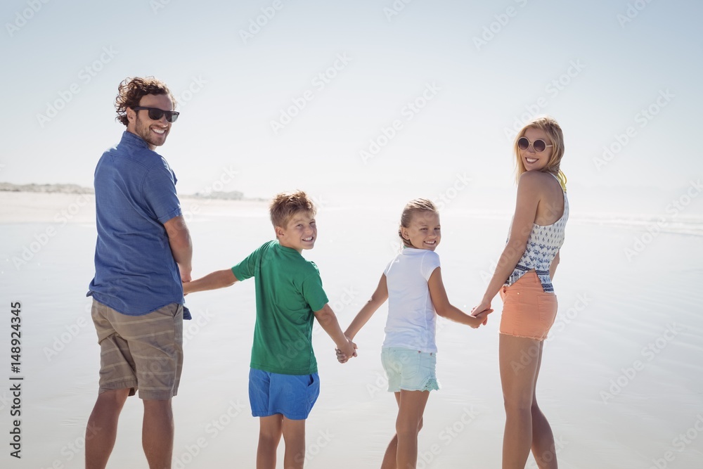 Portrait of family holding hands while standing on shore Portrait of family holding hands while standing on shore