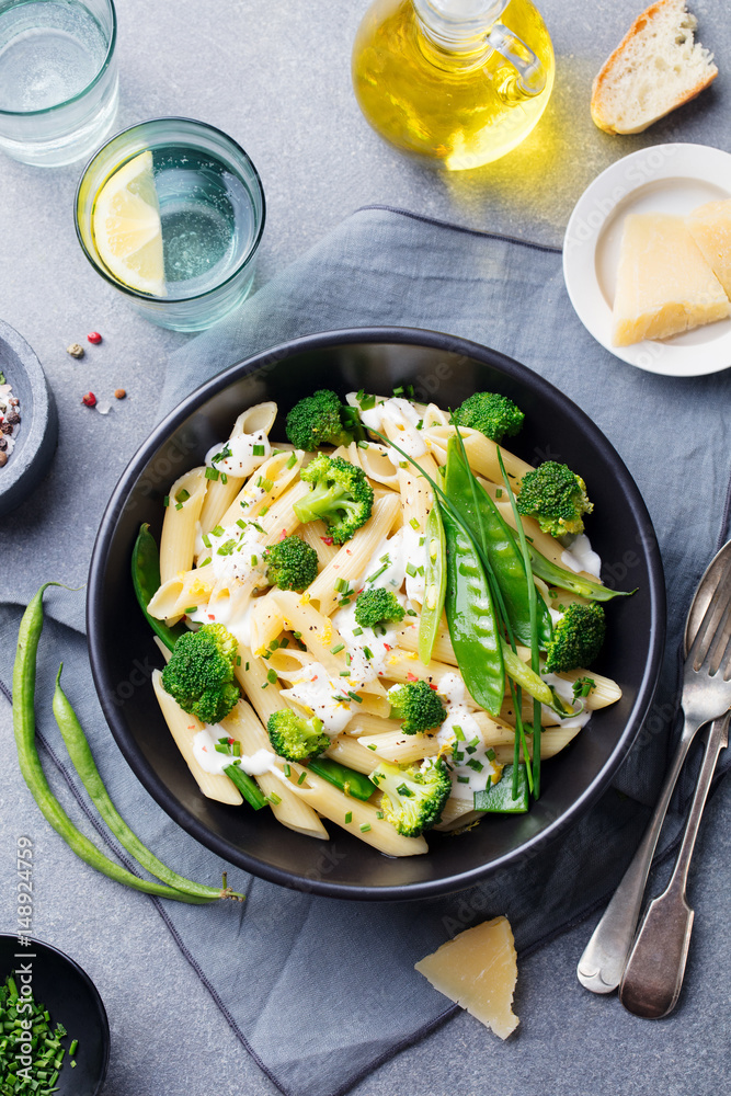 Pasta with green vegetables and creamy sauce in black bowl. Top view Pasta with green vegetables and creamy sauce in black bowl. Top view