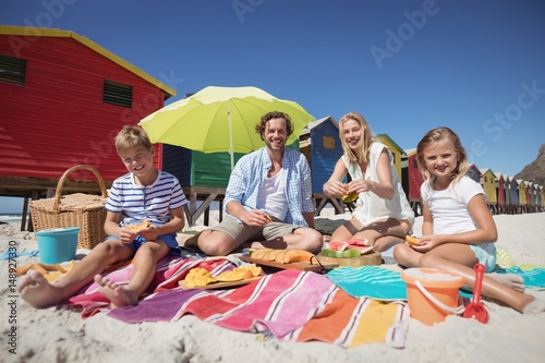 Portrait of happy family sitting together on blanket at beach