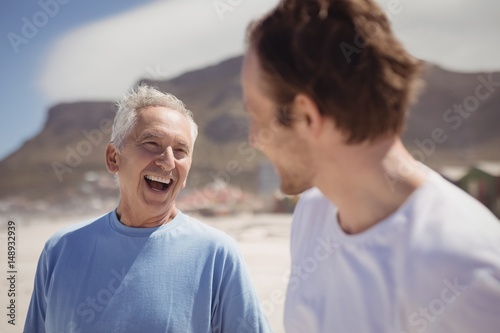Cheerful senior man with his son standing at beach