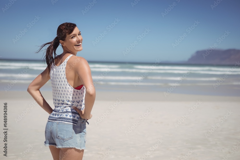 Portrait of happy woman with hands on hip standing at beach Portrait of happy woman with hands on hip standing at beach