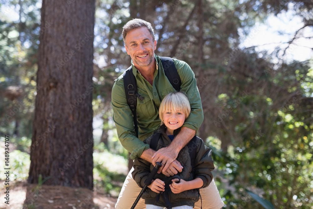 Happy father and son standing against trees in forest