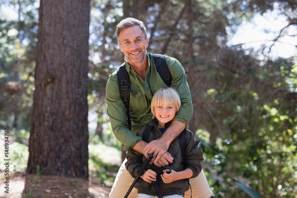 Happy father and son standing against trees in forest Happy father and son standing against trees in forest