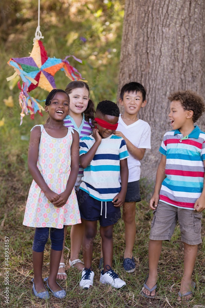 Fototapeta premium Friends standing with blindfolded boy