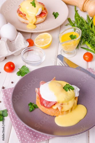 Eggs Benedict for breakfast on white wooden background