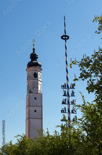 Typical Bavarian church tower and a traditional maibaum, maypole against the blue sky in Dorfen, Bavaria, Germany photo